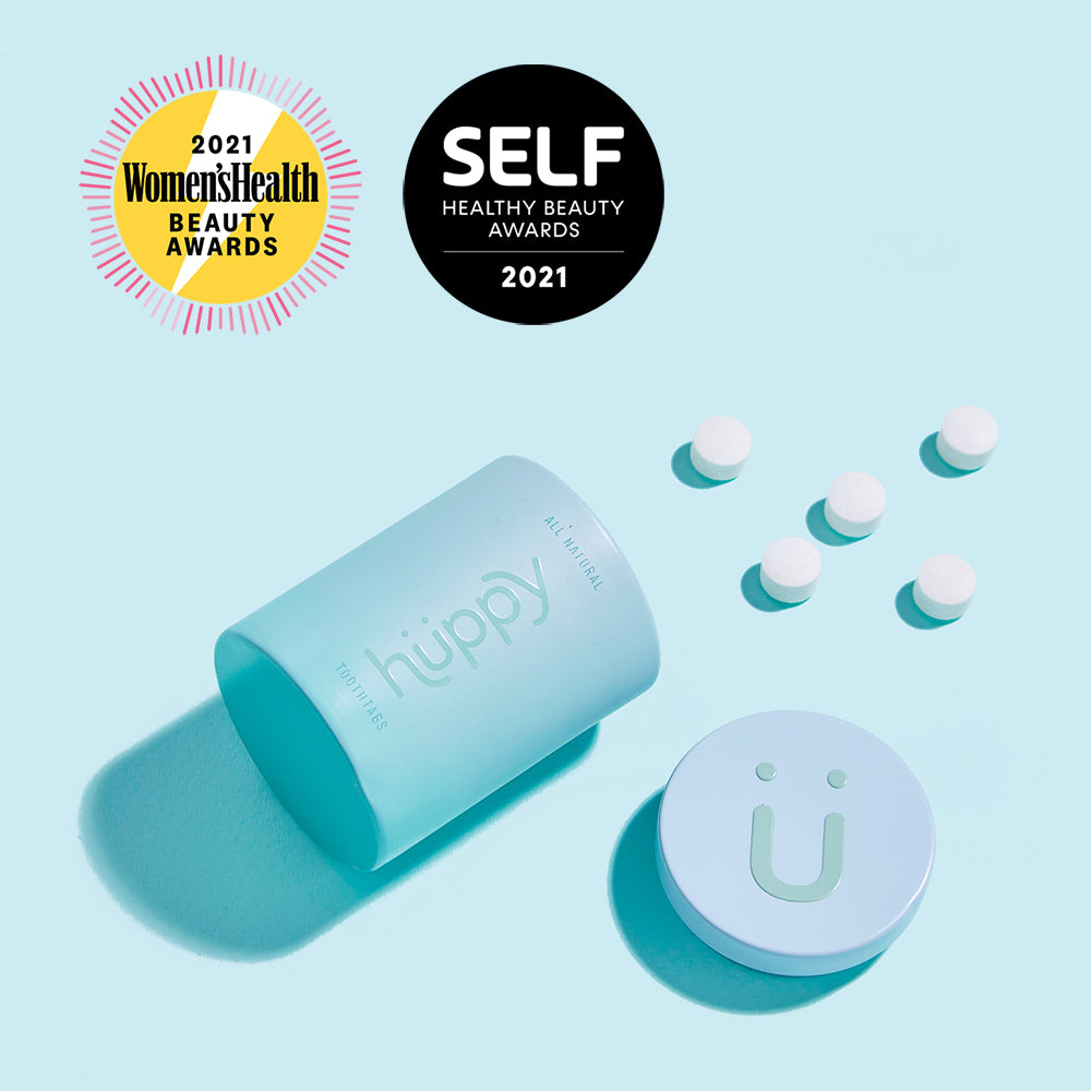 Toothpaste Tablets - Zero Waste Toothpaste - All-Natural, Plastic Free, Refillable, 62 ct. Blue huppy aluminum cup open with toothpaste tablets outside it. Awards labels at the top readh: 2021 Womens Health Beauty Awards and SELF Healthy Beauty Awards 2021.