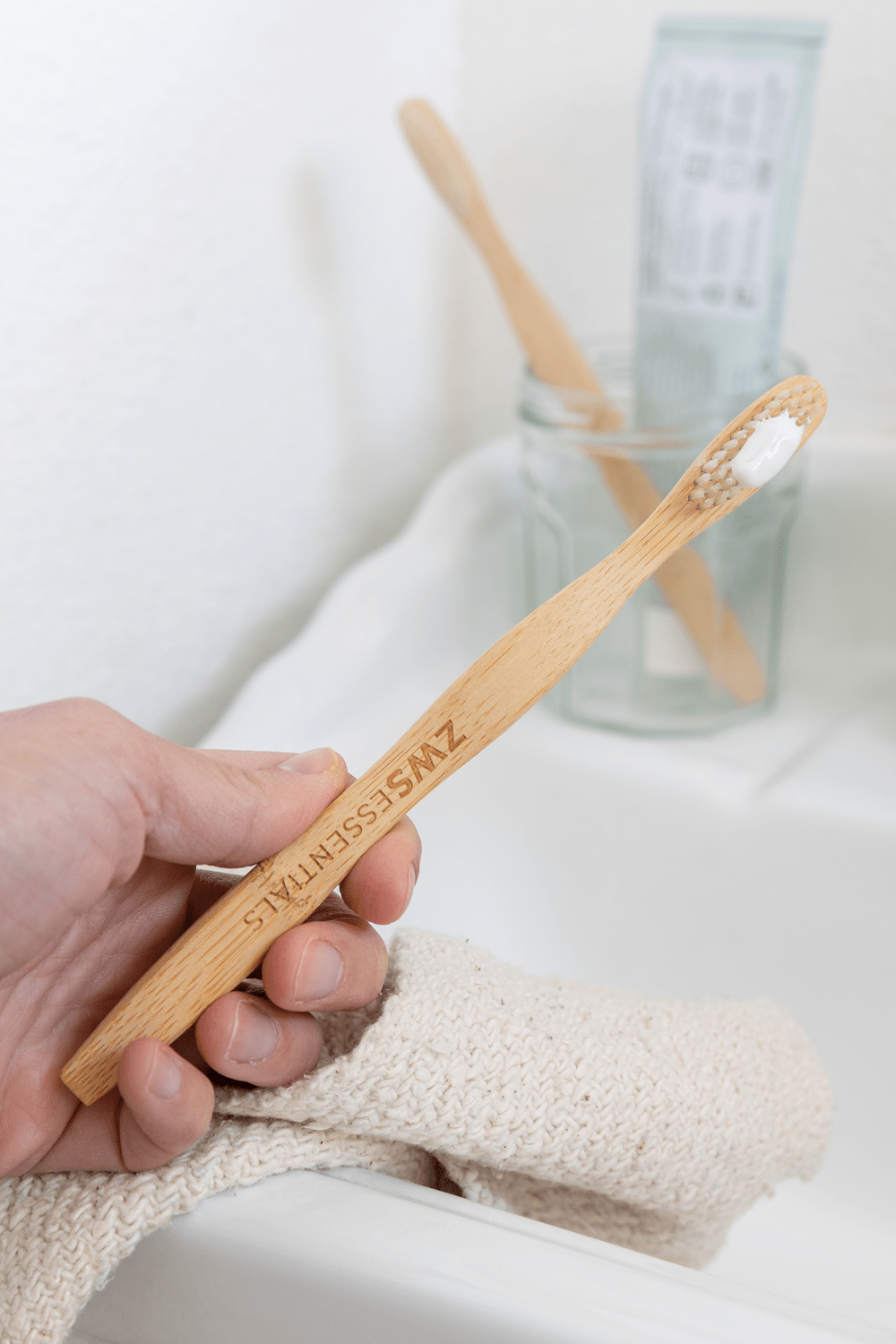 model holding bamboo toothbrush by sink